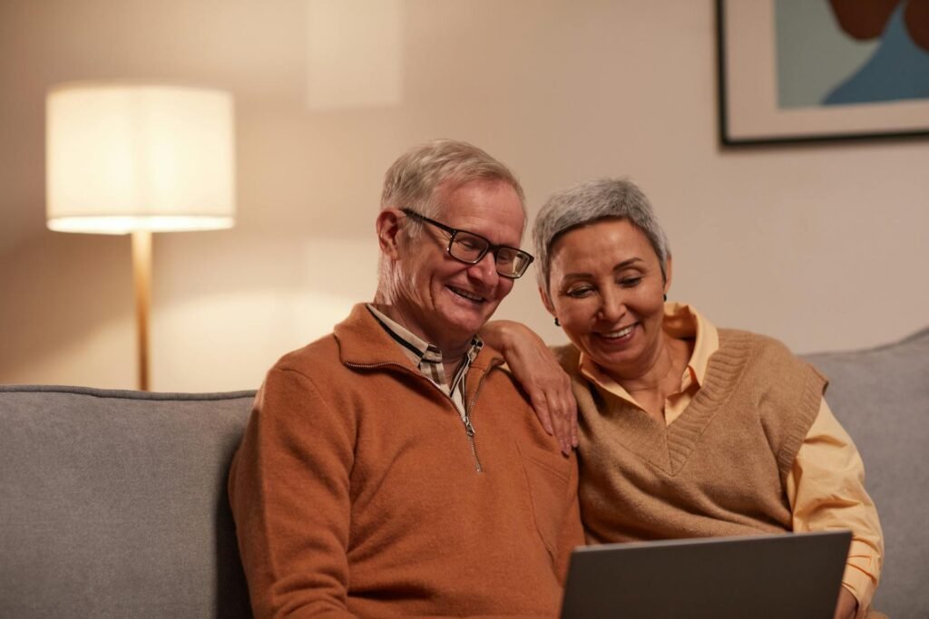 Senior couple enjoying time together on laptop indoors, smiling and relaxed.